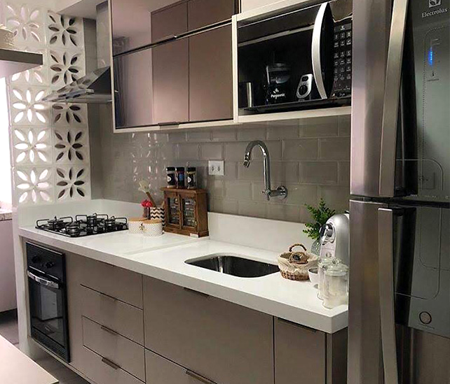Cozinha planejada com armários amadeirados, bancada clara e divisória vazada