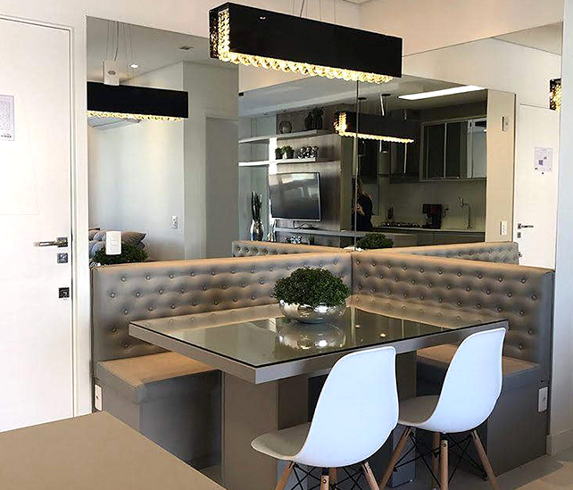 Sala de jantar com canto estofado, espelho, mesa e mobiliário planejado